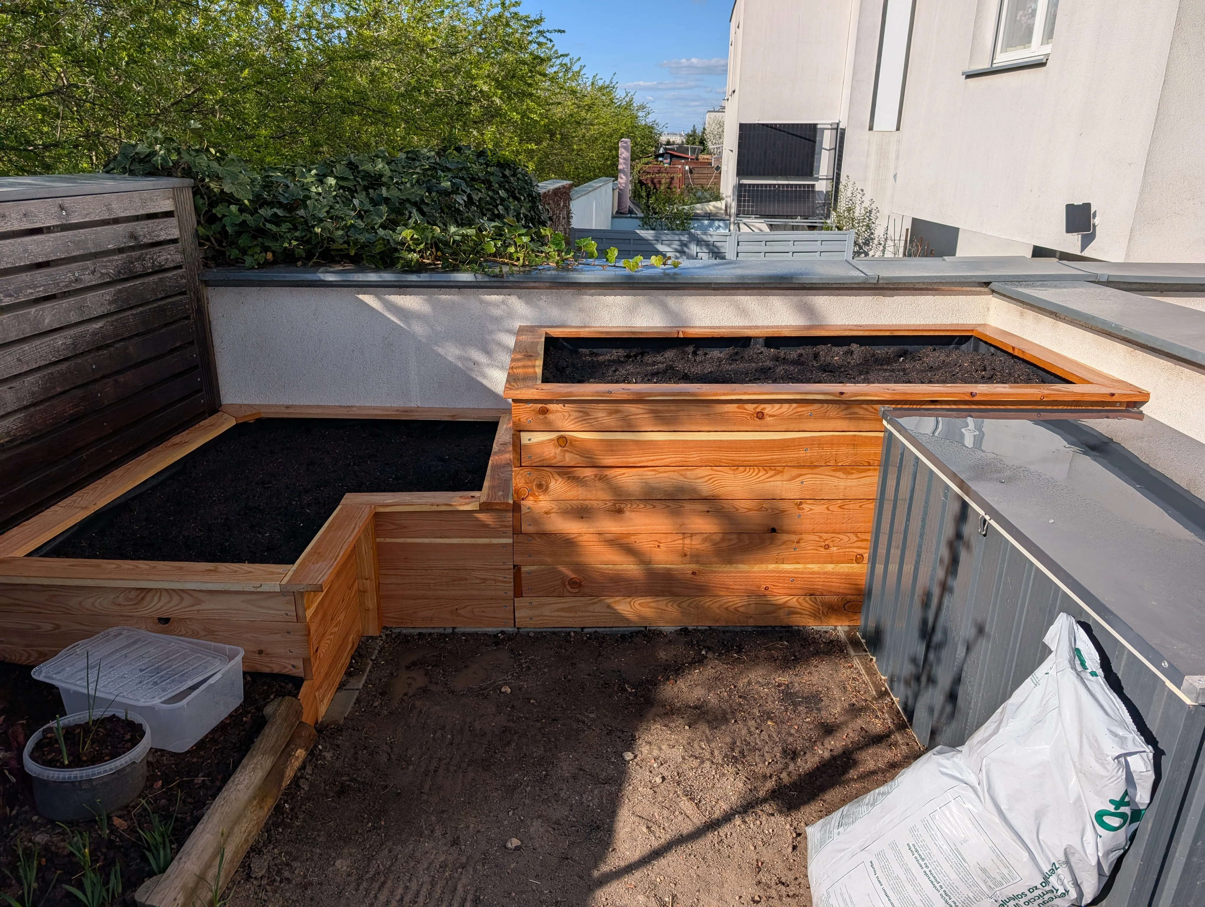 An L-shaped raised bed planter made of wood on a sunny day